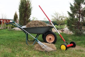 a wheelbarrow filled with mulch and other landscaping tools